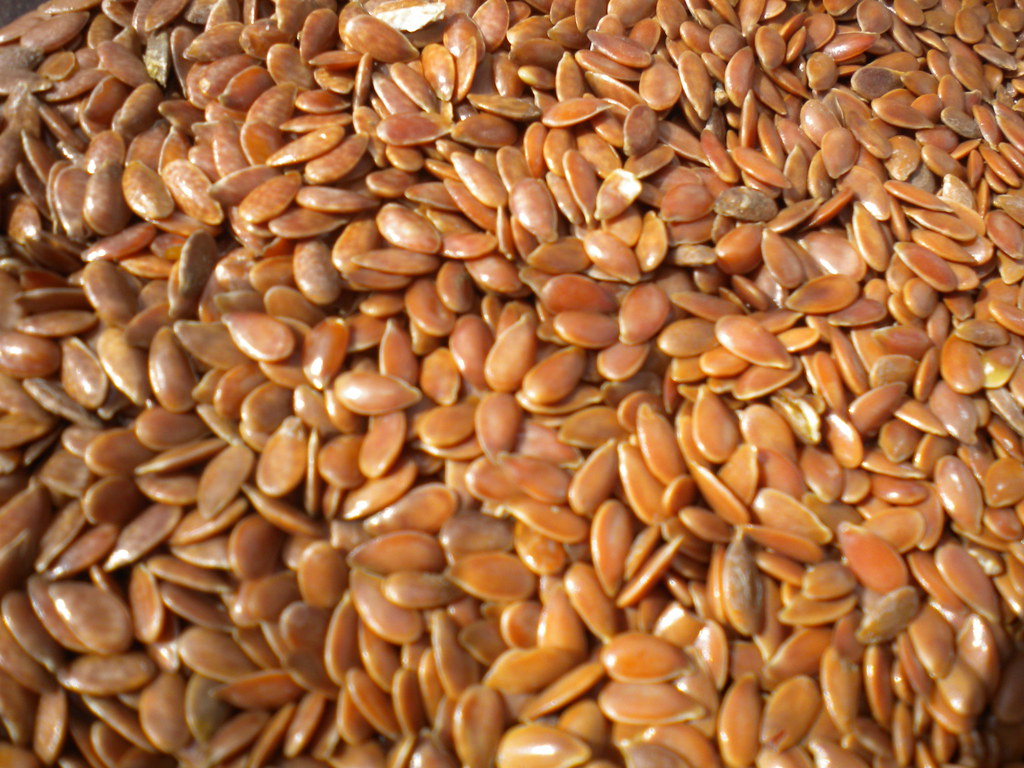 Flaxseed oil softgels and flax seeds on a white surface, representing flaxseed oil omega 3 supplements.