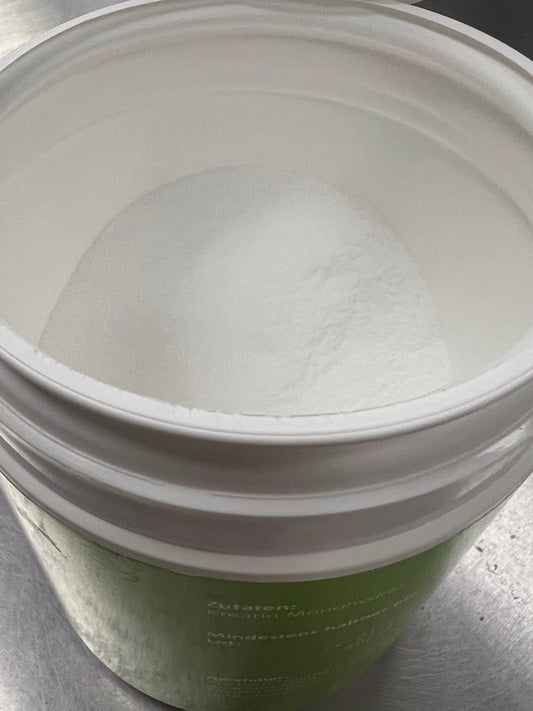 Creatine monohydrate dosage for muscle gain shown with a scoop of powder and dumbbells