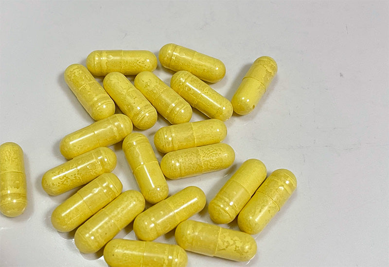 Quercetin for allergies supplement capsules on a wooden table with green leaves