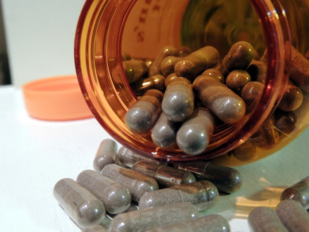 Dandelion root for water retention supplement capsules on a wooden table