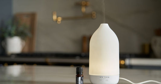 A sleek ultrasonic aromatherapy diffuser emitting a fine mist, sitting on a wooden shelf, part of a diffusers buying guide UK.