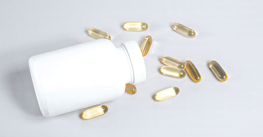 Bottle of astaxanthin softgels beside a few scattered capsules on a marble surface, illustrating astaxanthin for skin supplements.
