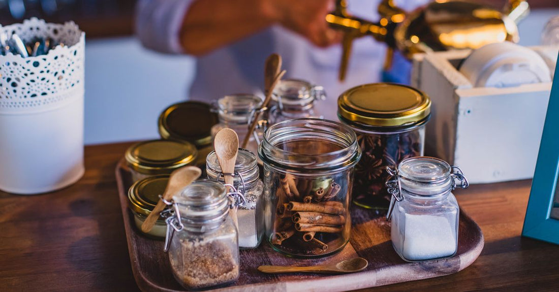 A close-up of fragrant cinnamon sticks and a jar of ground cinnamon on a rustic wooden surface, illustrating a cinnamon buying guide UK article.