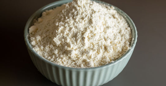 A small ceramic bowl filled with organic ashwagandha root powder beside a wooden spoon on a light surface, illustrating how to choose ashwagandha supplements in the UK.