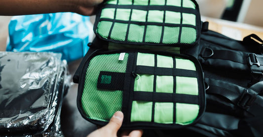 A set of colourful packing cubes and a clear toiletry bag laid flat on a white surface, illustrating an organisers & travel kits buying guide UK