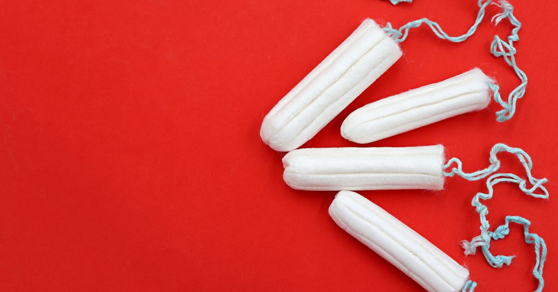 A flatlay of various tampon boxes and loose organic cotton tampons on a clean white surface, illustrating a tampons buying guide UK.