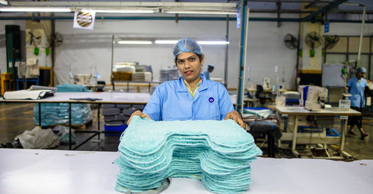 Stack of white reusable underpads for incontinence, neatly folded on a bedroom shelf