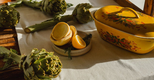 A bottle of artichoke extract capsules beside fresh artichokes on a wooden surface, illustrating how to choose artichoke supplements.