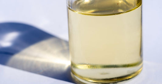 Glass bottle of MCT oil on a white background, showing clear liquid, representing how to choose MCT oil UK.