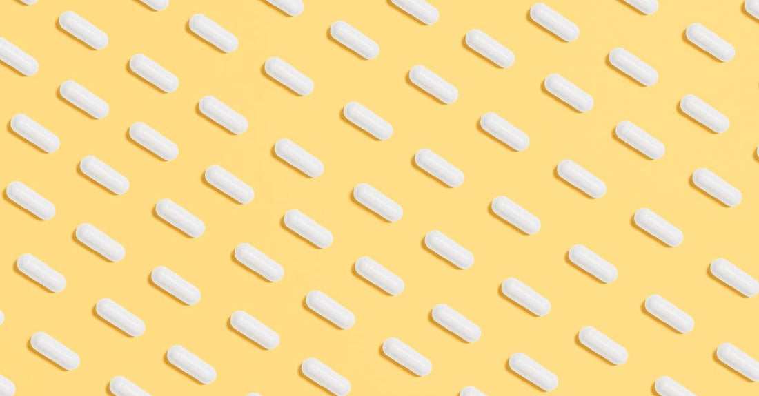 A close-up of acidophilus probiotic supplement capsules spilling from a glass bottle onto a light surface, representing an acidophilus buying guide UK.