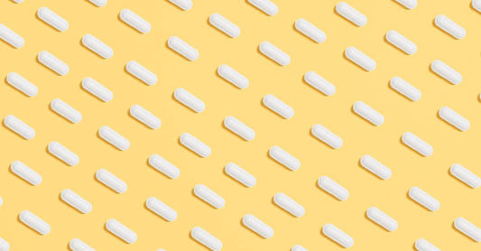 A close-up of acidophilus probiotic supplement capsules spilling from a glass bottle onto a light surface, representing an acidophilus buying guide UK.