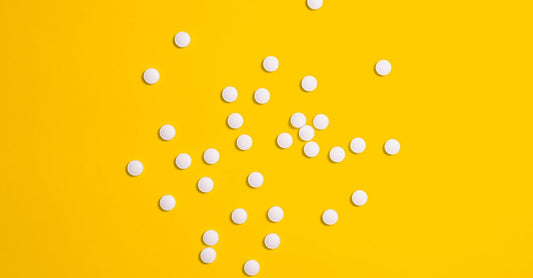 B12 oral sublingual tablets next to a glass of water, illustrating the B12 injections vs oral comparison for UK shoppers.