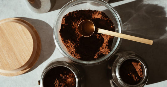 Jar of mushroom coffee with lions mane powder on a wooden surface next to a coffee cup.