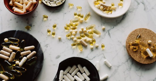 A flatlay of vitamin supplement bottles and natural health products on a light wood surface, illustrating how to choose home page UK design elements.