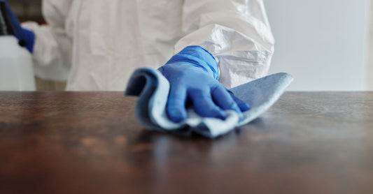 A canister of antibacterial wipes for surfaces on a clean kitchen worktop, surrounded by fresh hygiene accessories.