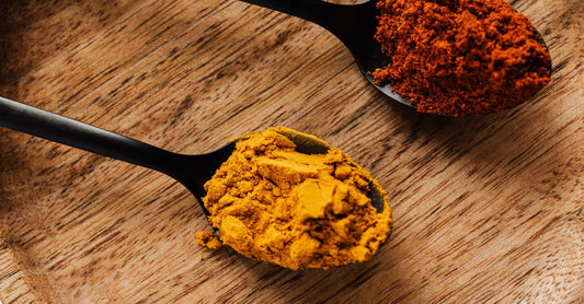 Turmeric curcumin with black pepper supplement capsules spilled from a bottle on a clean surface, UK supplement photography.