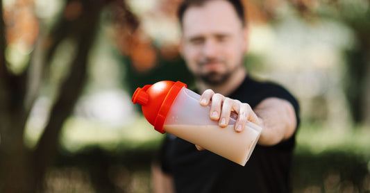 Insulated stainless steel shaker bottle for protein shakes on a gym bench