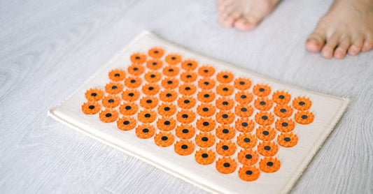 A flatlay of an acupressure kit with ear seeds, a stainless steel pen, and a massage roller on a light background, illustrating an acupuncture buying guide.