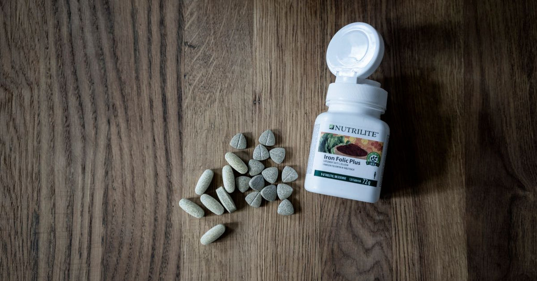 Bottle of folate supplement next to a glass of water, illustrating folate vs folic acid pregnancy routine