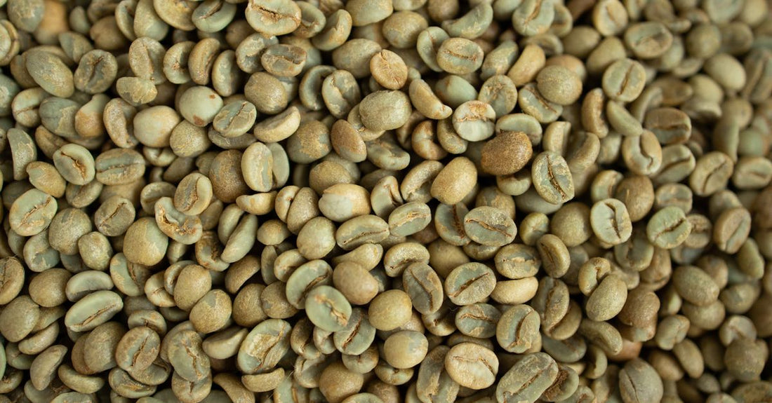 Green coffee bean supplement capsules next to a few raw green coffee beans on a clean surface, illustrating weight loss support.