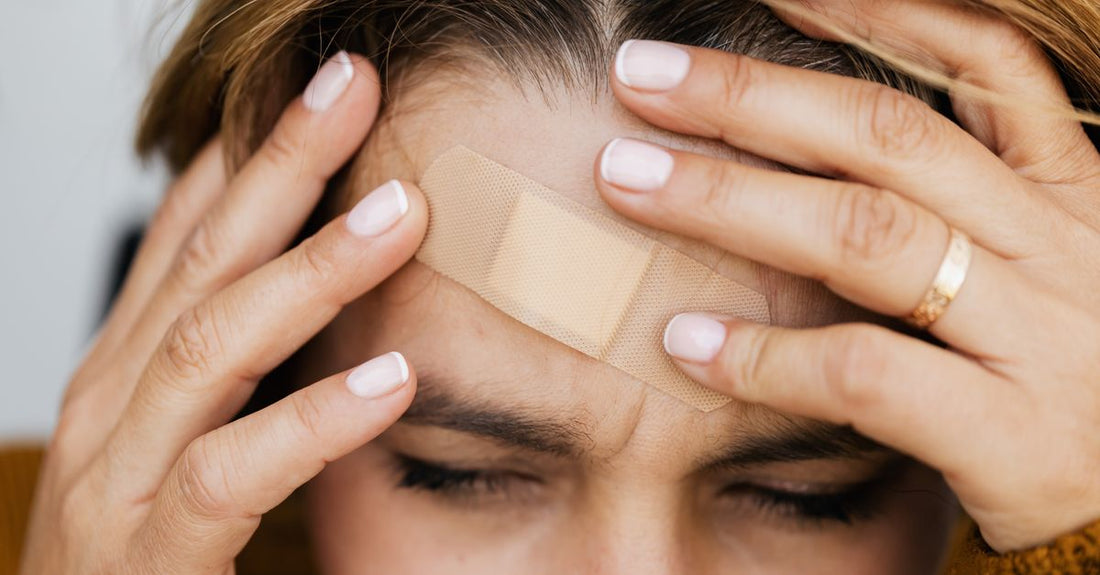 A flat lay of various adhesive bandage types – cohesive wraps, bordered gauze dressings, and waterproof plasters – on a clean white surface, illustrating how to choose adhesive bandages for different injuries.