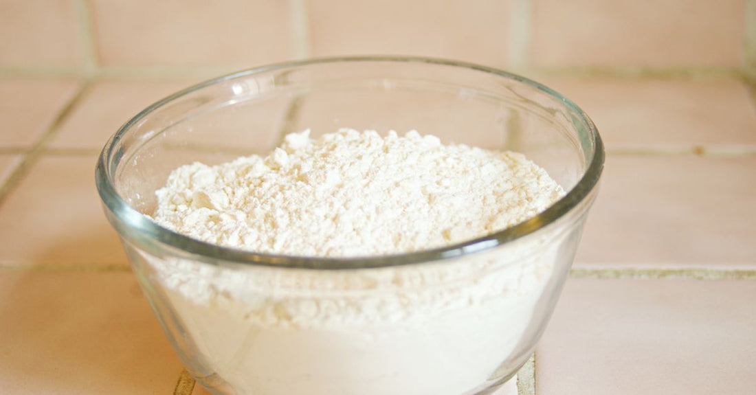 A wooden bowl filled with fine ashwagandha root powder beside a small spoon, embodying the focus of this ashwagandha buying guide.