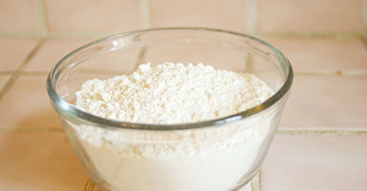 A wooden bowl filled with fine ashwagandha root powder beside a small spoon, embodying the focus of this ashwagandha buying guide.