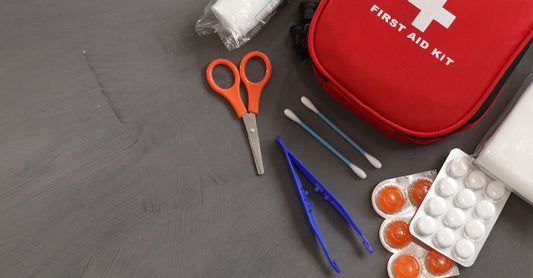 A comprehensive UK first aid kit flatlay showing bandages, scissors, antiseptic wipes, and burn dressings on a clean white background.
