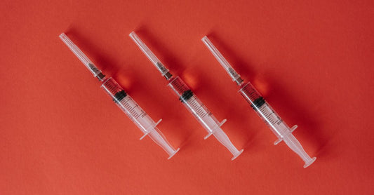 A flatlay of individually wrapped alcohol swabs for injections on a clean white surface with a syringe and vial