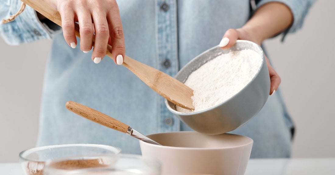 A wooden bowl filled with green hemp protein powder and a wooden scoop on a light kitchen worktop, illustrating hemp protein powder benefits for UK shoppers.