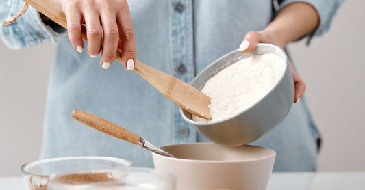A wooden bowl filled with green hemp protein powder and a wooden scoop on a light kitchen worktop, illustrating hemp protein powder benefits for UK shoppers.