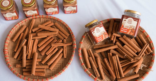 A small glass jar of ground cinnamon powder with a wooden spoon on a light kitchen surface, illustrating how to choose cinnamon UK