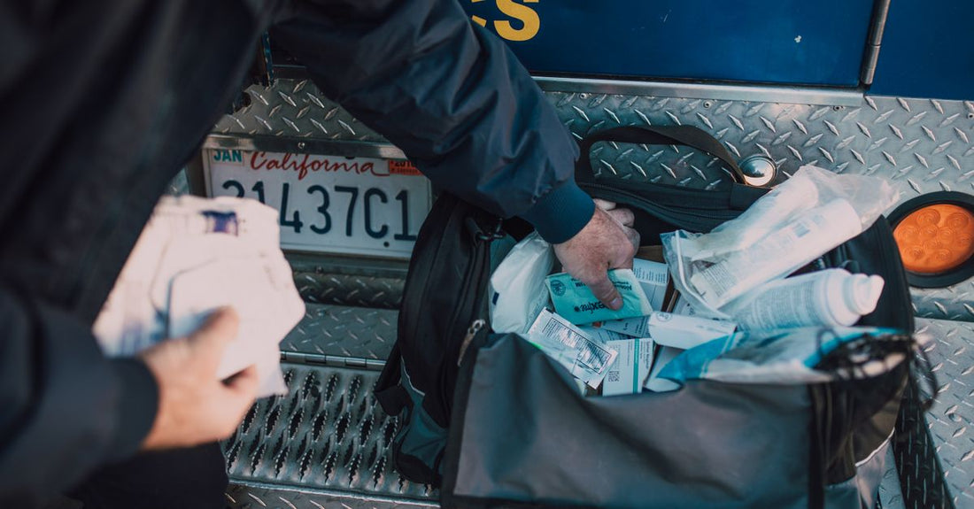 Assorted adhesive bandages including fabric and hydrocolloid types laid flat, with a box of Nutrisentra first‑aid supplies in the background.
