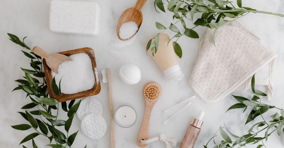 A flatlay of white cotton cleansing cloths and a wooden dish on a marble surface, illustrating a cleansing cloths, swabs & wipes buying guide UK.