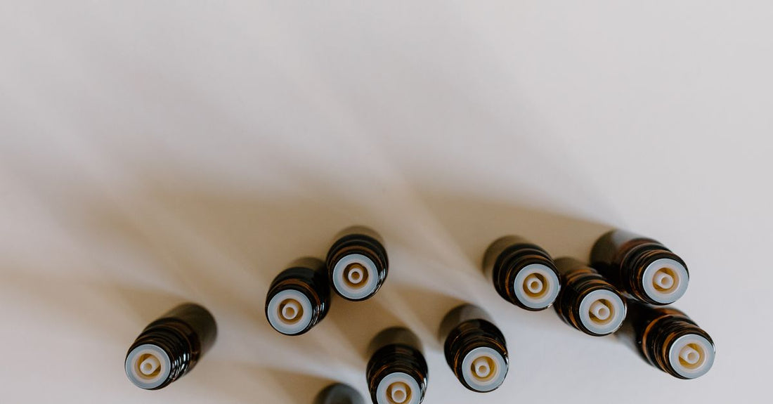 A flatlay of amber essential oil bottles with wooden caps, showcasing a variety of essential oil sets available in the UK.