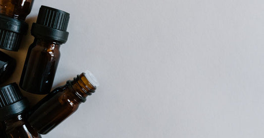 Essential oil sets buying guide UK featuring a flatlay of amber bottles with wooden caps on a neutral background.