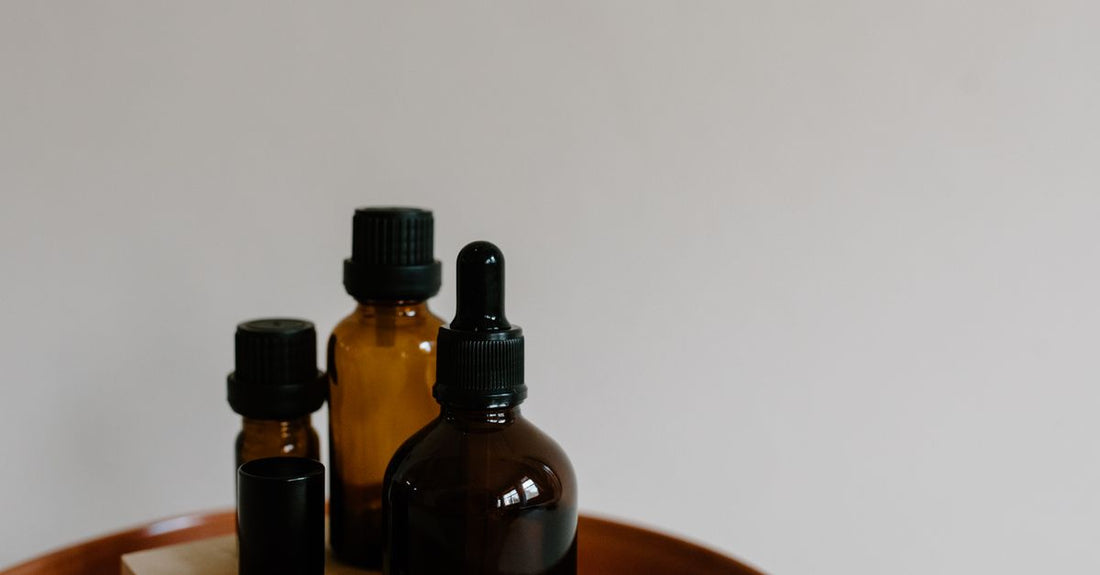 A glass bottle of golden black currant seed oil on a neutral surface, highlighting its use for skin nourishment.