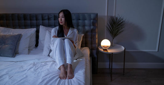 A compact white noise sound machine on a bedside table in a UK bedroom, featuring multiple sound options and a night light.