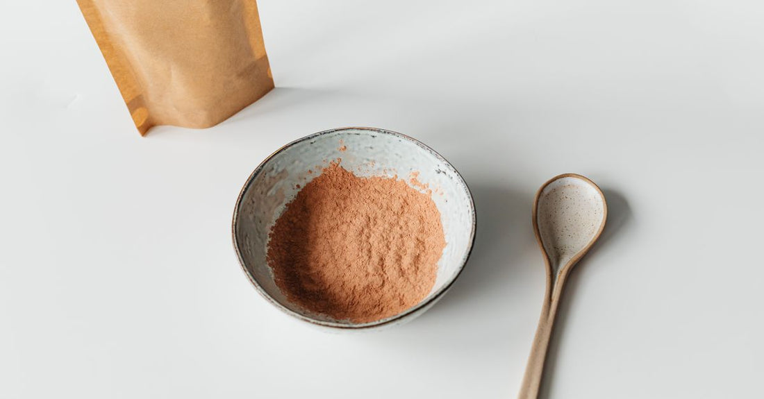 A bowl of fine slippery elm bark powder with a wooden spoon on a neutral background