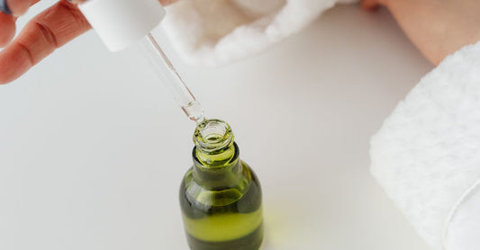 A glass bottle of oregano oil with a dropper and fresh oregano sprigs on a neutral background, illustrating the best oregano UK 2026 supplements.