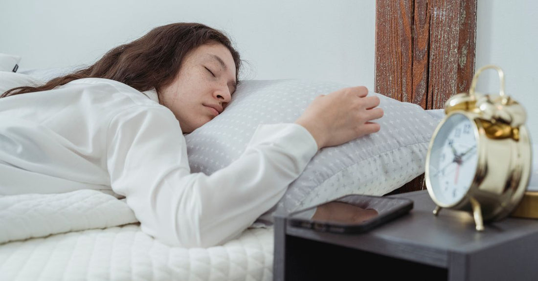 A sleek white noise sleep sound machine on a bedside table in a dimly lit bedroom, representing a sleep sound machines buying guide UK.