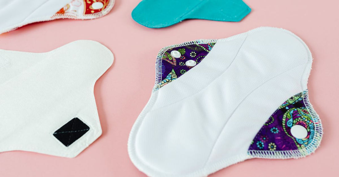 Stack of soft, quilted reusable underpads in neutral tones arranged on a light wooden surface, illustrating a reusable underpads buying guide UK.