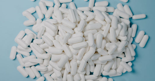 A bottle of nitric oxide supplement for ED on a white background with capsules spilling out
