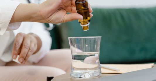Trace minerals for hydration — a glass bottle of liquid mineral drops next to a glass of water on a clean surface.