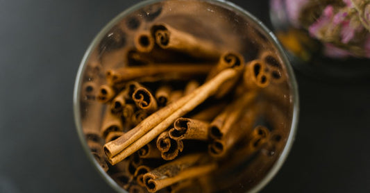 Best cinnamon UK 2026: a glass jar of Ceylon cinnamon sticks beside a bowl of ground cinnamon on a wooden surface.