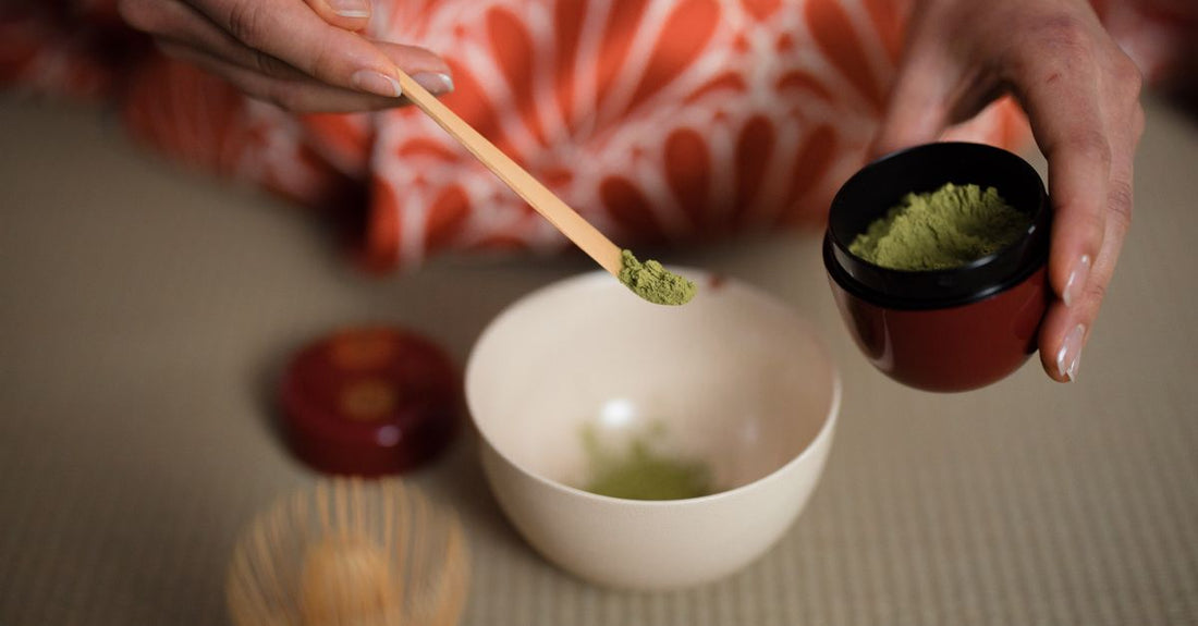 A bowl of vibrant matcha green tea powder with a bamboo whisk on a neutral background, illustrating how to choose green tea UK.