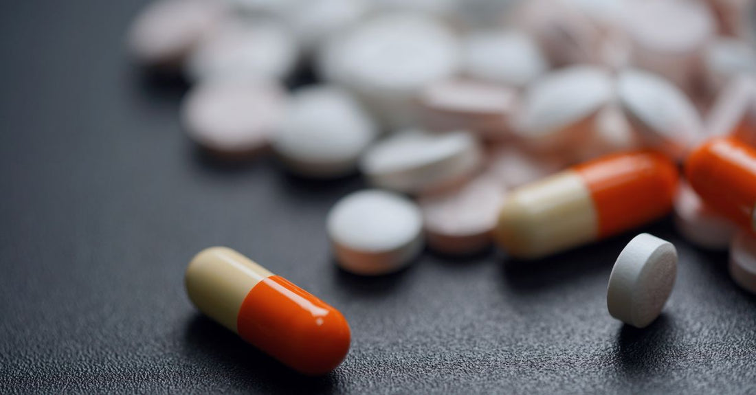 Close-up of niacin (vitamin B3) supplement capsules spilling from a bottle onto a clean white surface, illustrating how to choose B3 (niacin) based on form and quality.