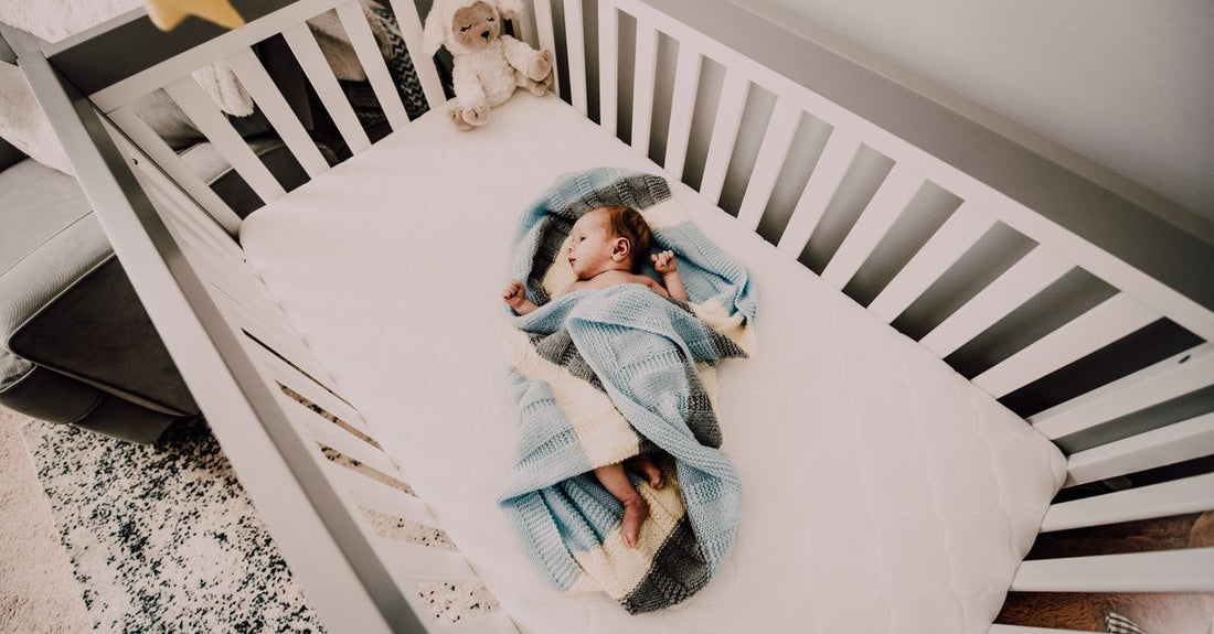 White noise machine for baby on a nursery shelf with soft toys and a blanket