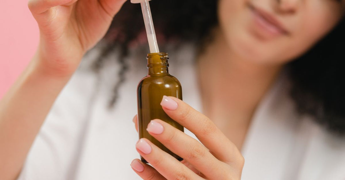 A glass bottle of niacinamide serum beside a small mortar filled with vitamin B3 capsules, on a white marble surface.